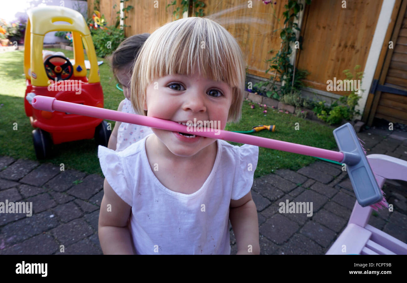 Blonde baby girl standing on patio holding broom Stock Photo - Alamy