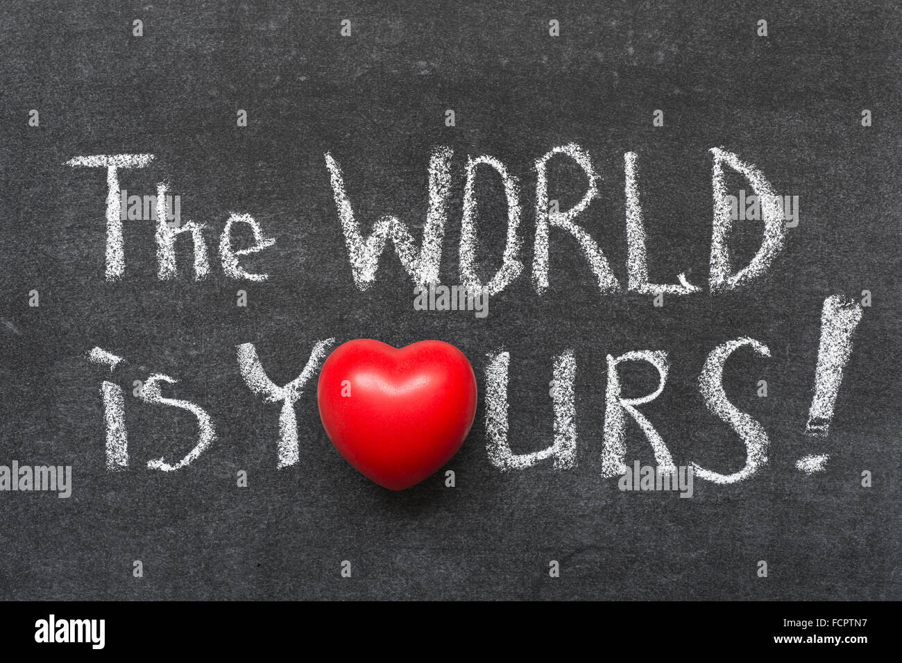 the world is yours exclamation  handwritten on blackboard with heart symbol instead of O Stock Photo