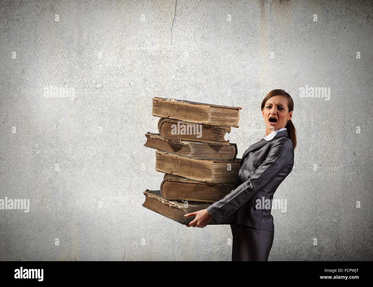 Young businesswoman carrying pile of old books Stock Photo - Alamy