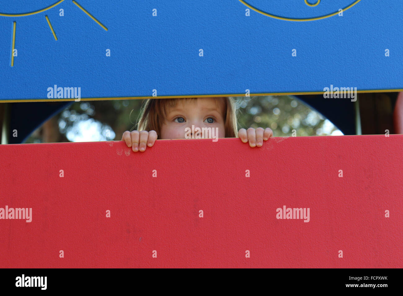 A child peeps through a playground in Calpe, Spain. Stock Photo