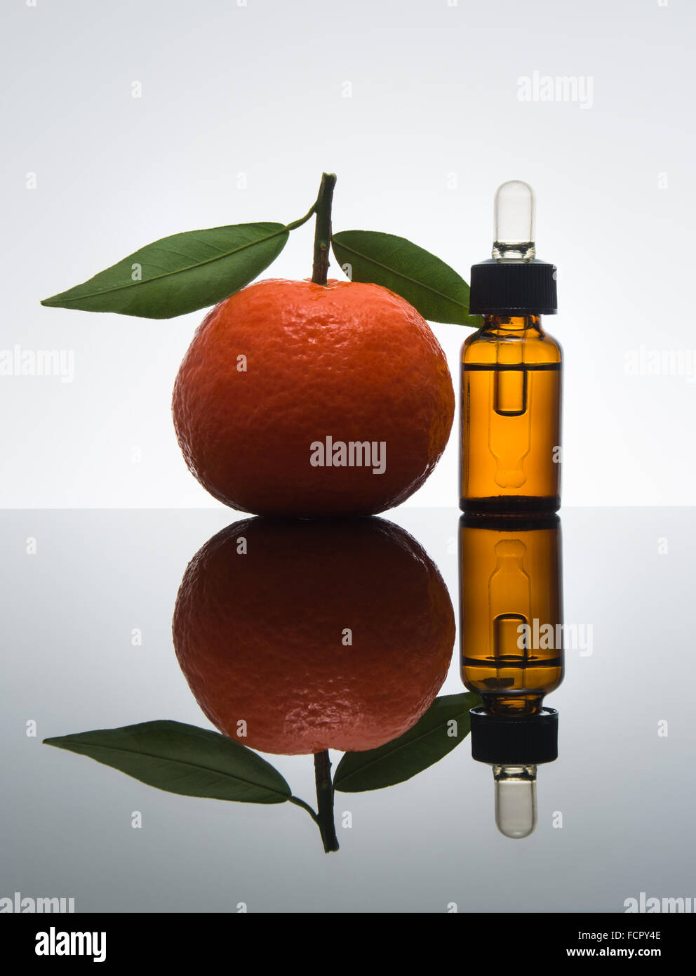 Mandarin / tangerine essential oil in amber glass bottle with fresh mandarin / tangerine with leaves and dropper Stock Photo