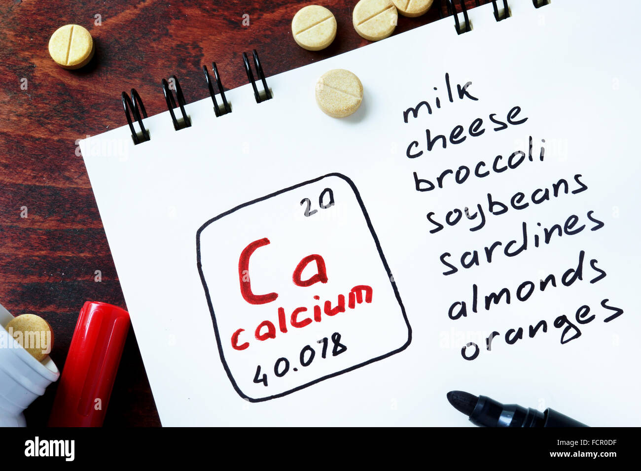 Notepad with calcium  and pills on the table. Stock Photo