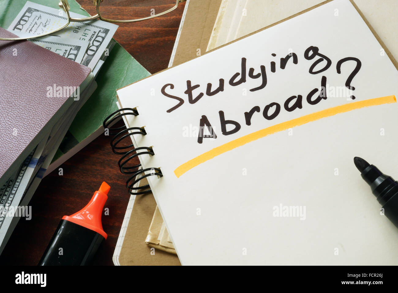 Notepad with Studying Abroad? on the wooden table. Stock Photo