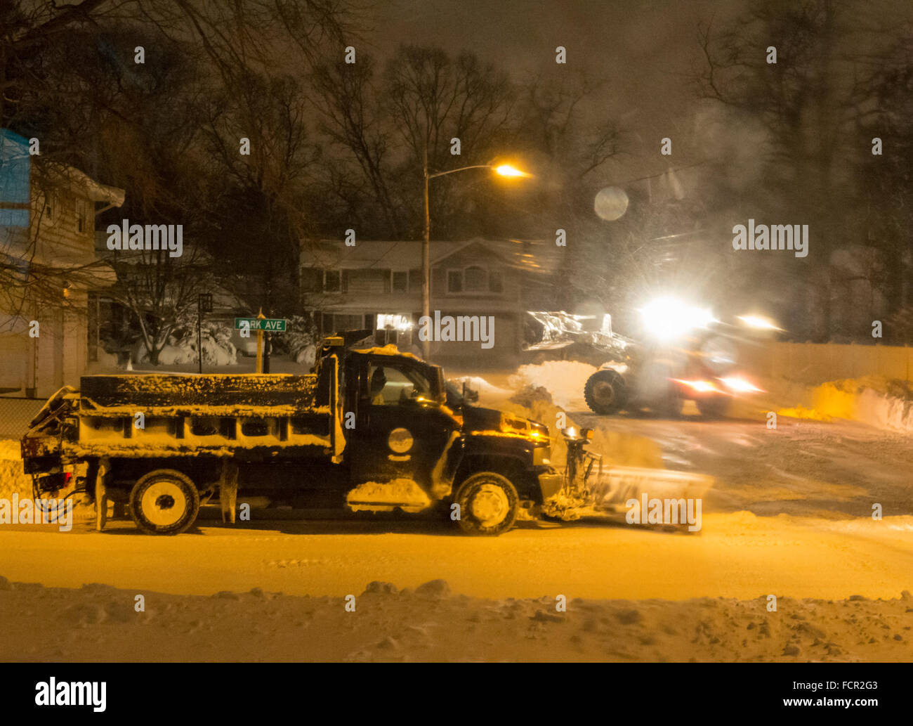 Merrick, New York, USA. 24rd January 2016. Two Town of Hempstead snowplows, a small one plowing out a cul de sac, dead end side street, and a large plow on the bigger road leading to it, are clearing roads while Blizzard Jonas continues to bring dangerous snow and gusting winds to Long Island. Gov. Cuomo banned travel, shutting down L.I.'s roads and railroads, due to hazardous conditions, and the winter Storm of 2016 has already dropped about two feet of snow on the south shore town. Credit:  Ann E Parry/Alamy Live News Stock Photo