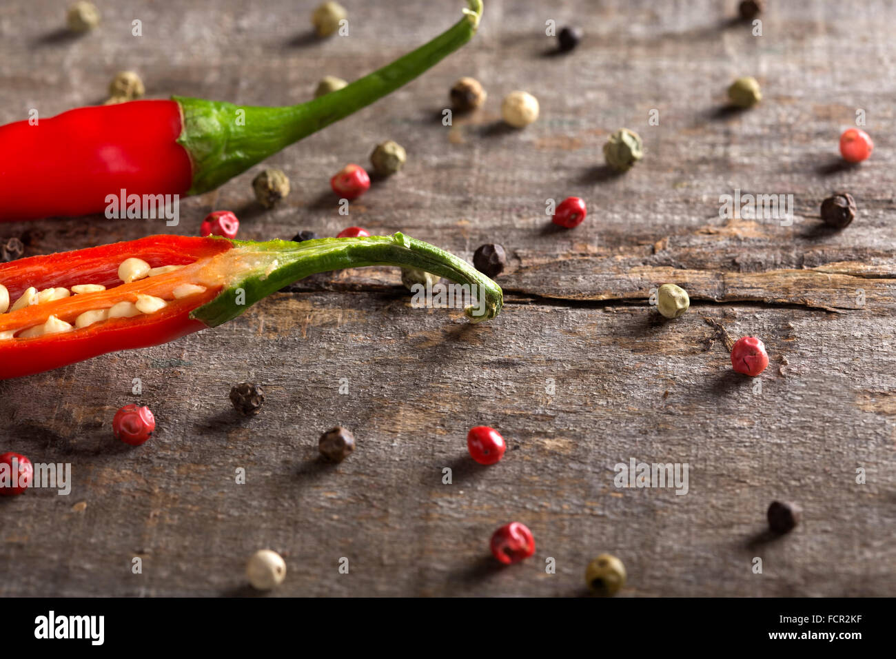 Red chili peppers on wood with peppercorns Stock Photo