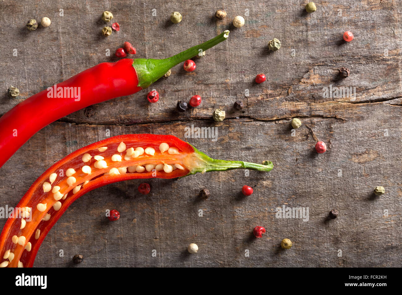 Red chili peppers on wood with peppercorns Stock Photo