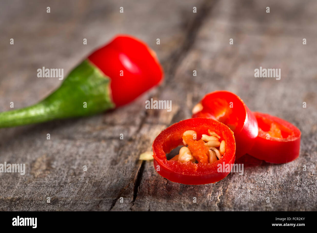 Red chili peppers slices over wooden background Stock Photo