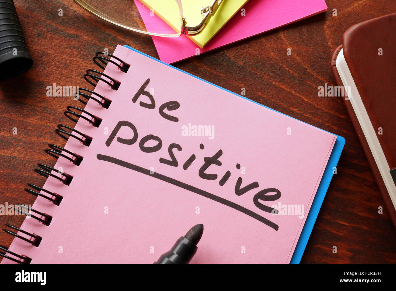 Notebook with the words Be positive  on the table. Stock Photo