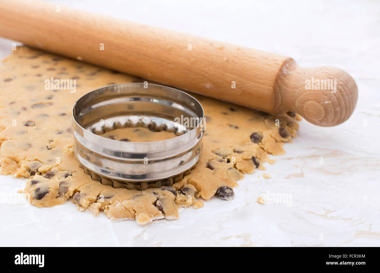 Cookie cutter and wooden rolling pin on rolled out peanut butter and
