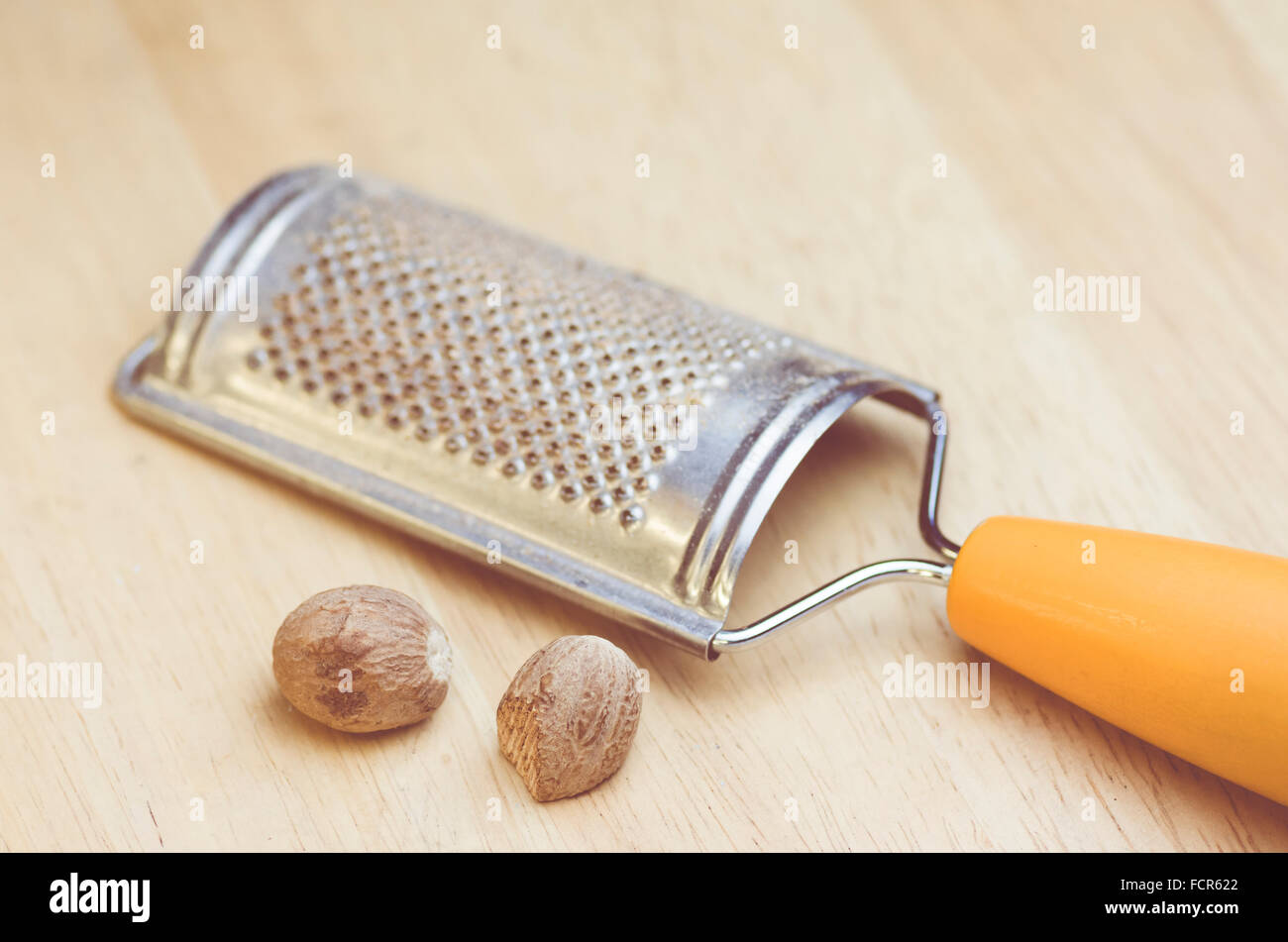 metal nutmeg hand grater and nutmegs on a wood background Stock Photo