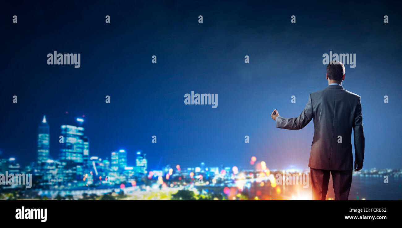 Rear view of businessman looking at night city Stock Photo - Alamy