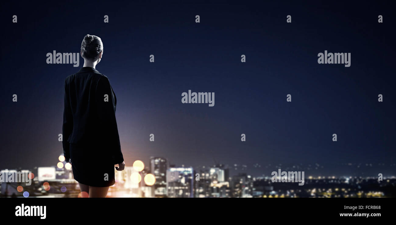 Rear view of businesswoman looking at night city Stock Photo - Alamy