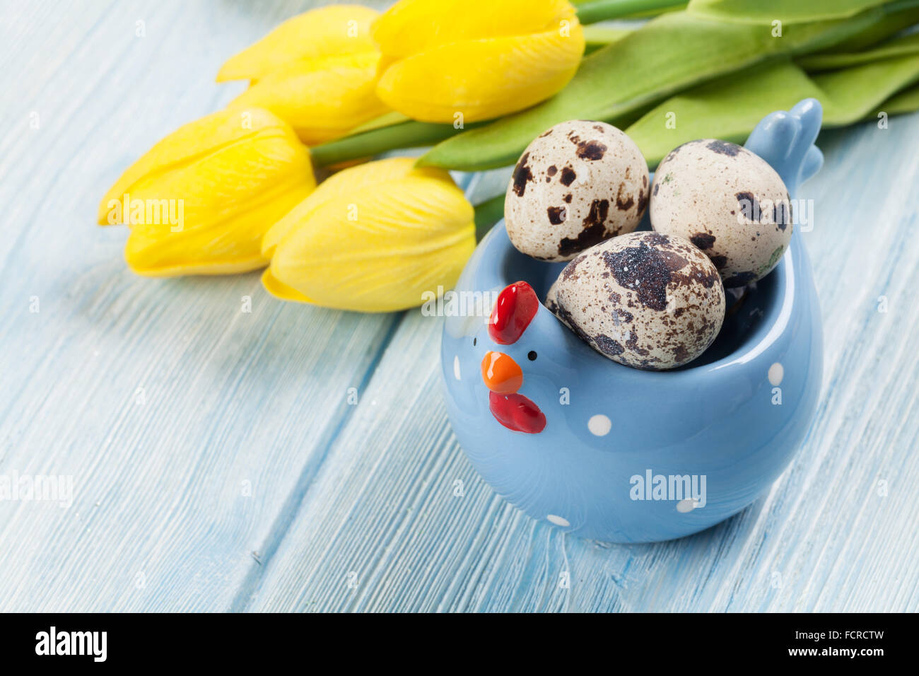 Easter card with eggs and yellow tulips over blue wooden table Stock ...