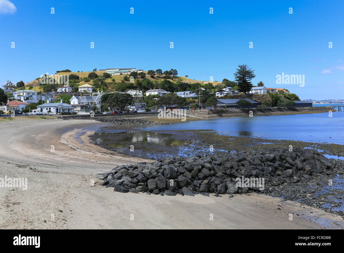 Rock groynes help to stabilize the beach on Torpedo Bay at Devonport, Auckland, New Zealand. Stock Photo