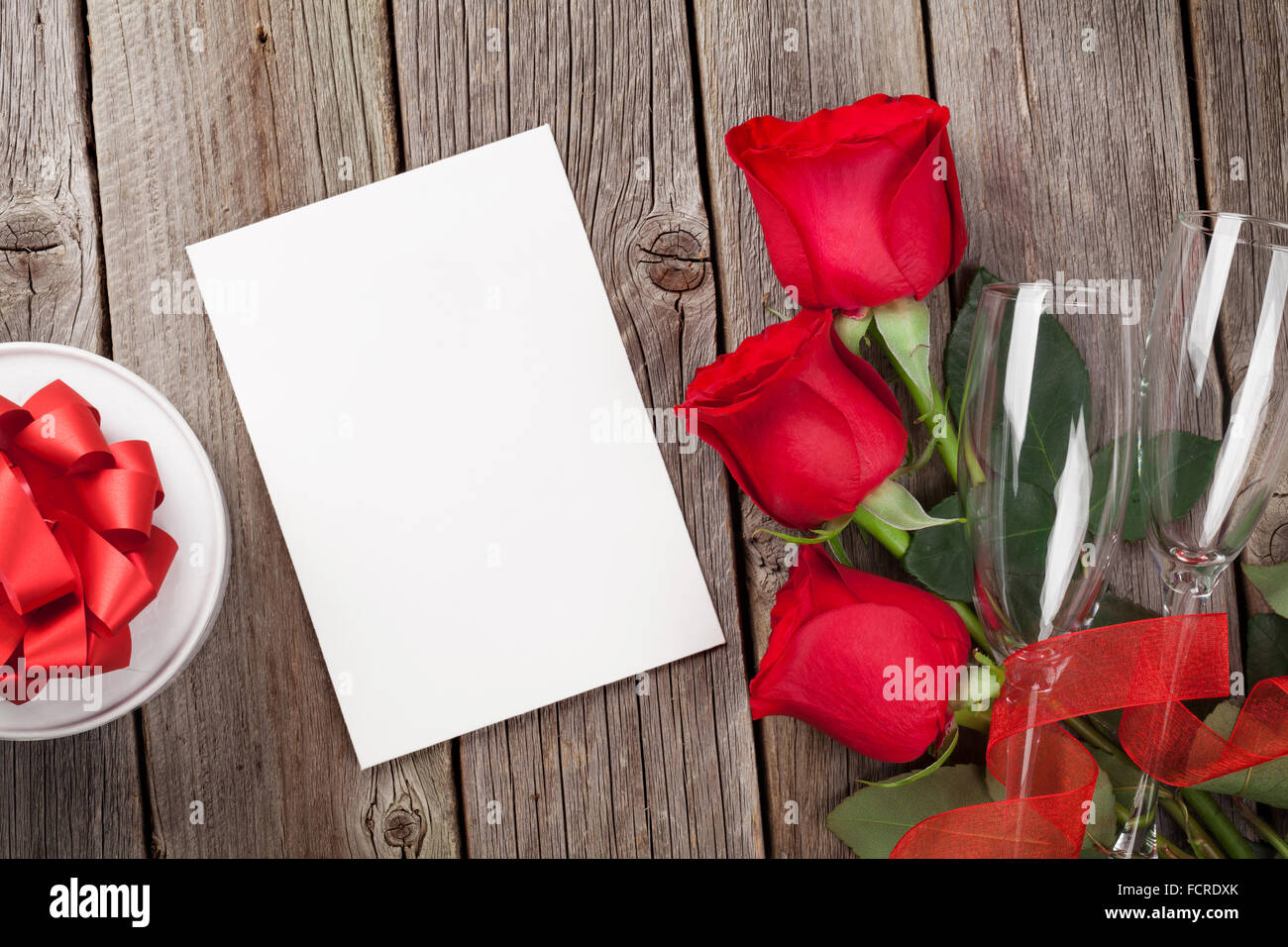 Valentines day greeting card, gift box and red roses on wooden table ...