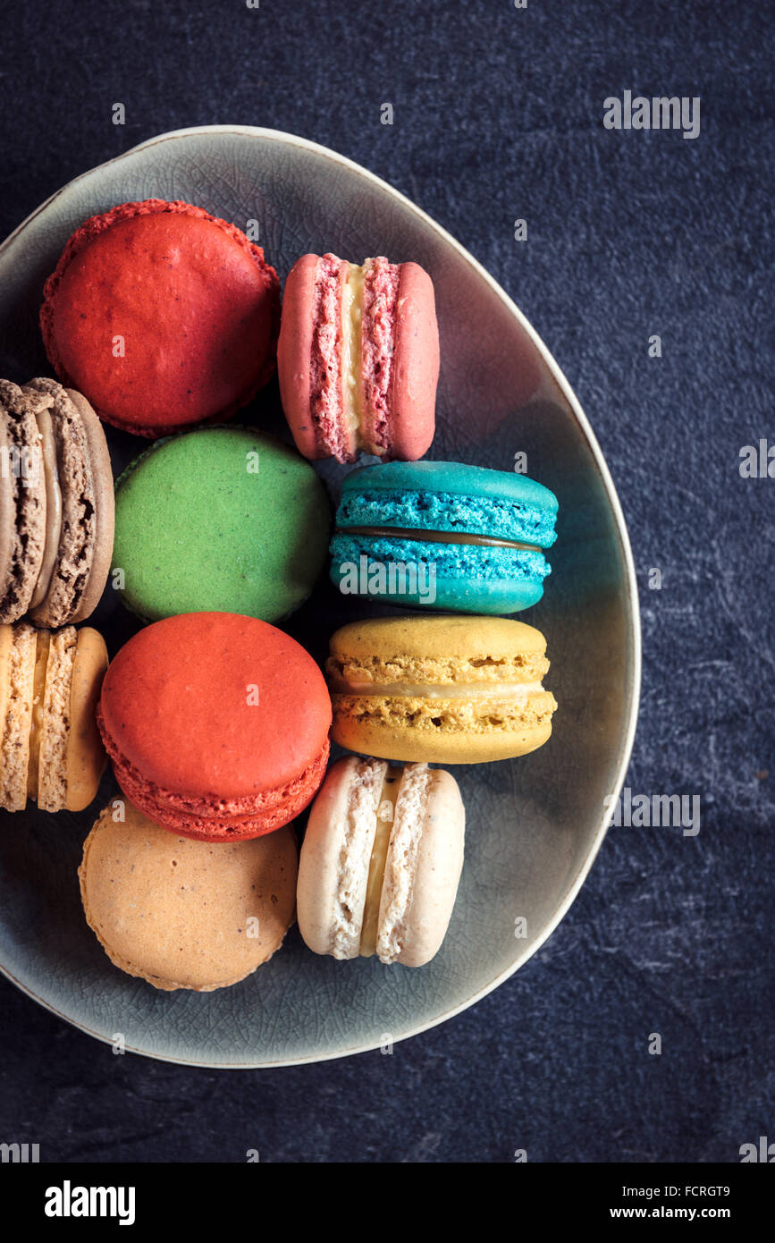Sweet and colorful macaroon cookies in the plate on dark background,selective focus Stock Photo