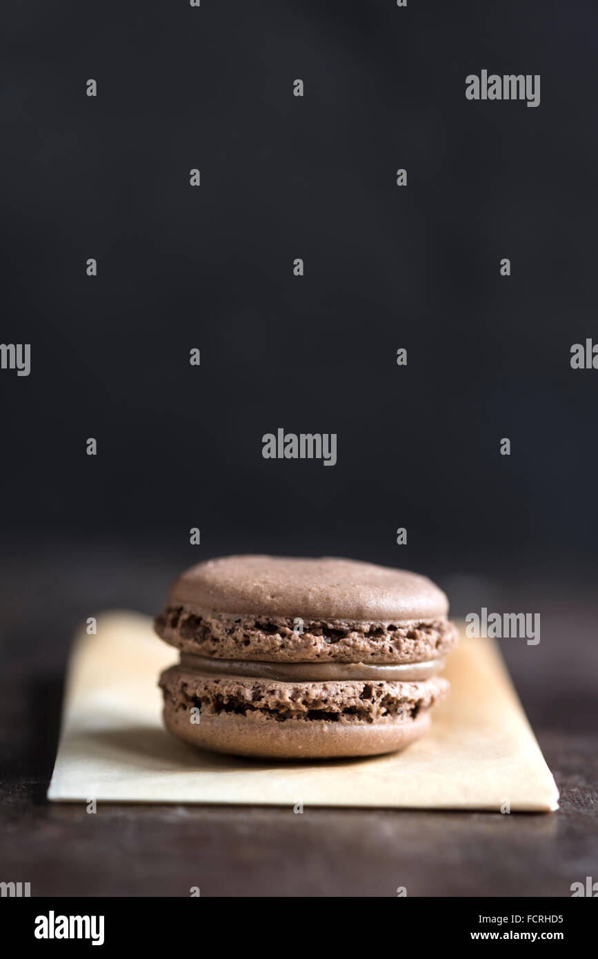 Single chocolate macaroon cookie on dark background with blank spae,selective focus Stock Photo