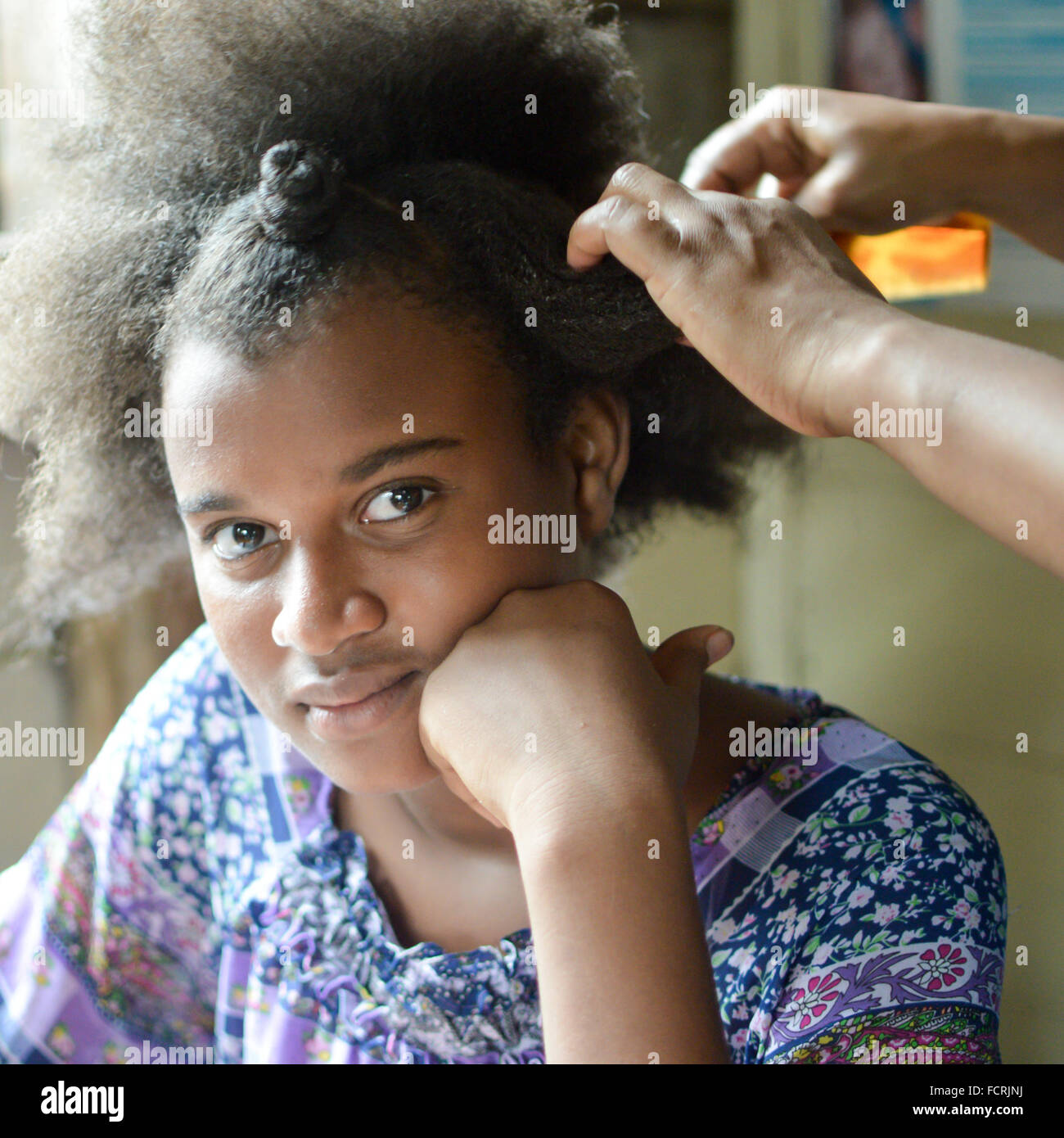 Pearl Lagoon, Nicaragua - July 16, 2015:  Beautiful Creole girl with funky hair gets a hairdo by her mother. Stock Photo