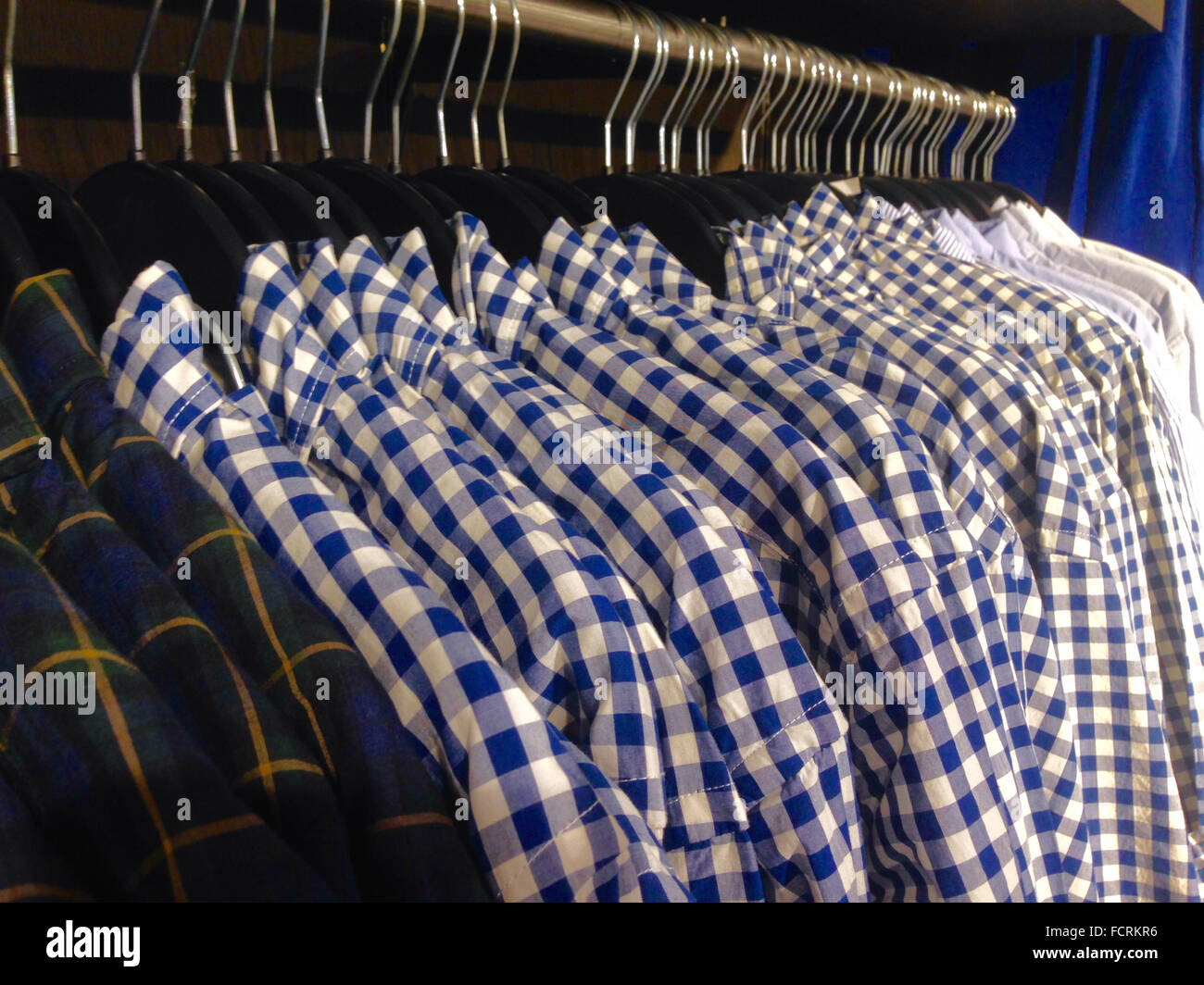 Hanger full of men's chequered shirts at shop Stock Photo