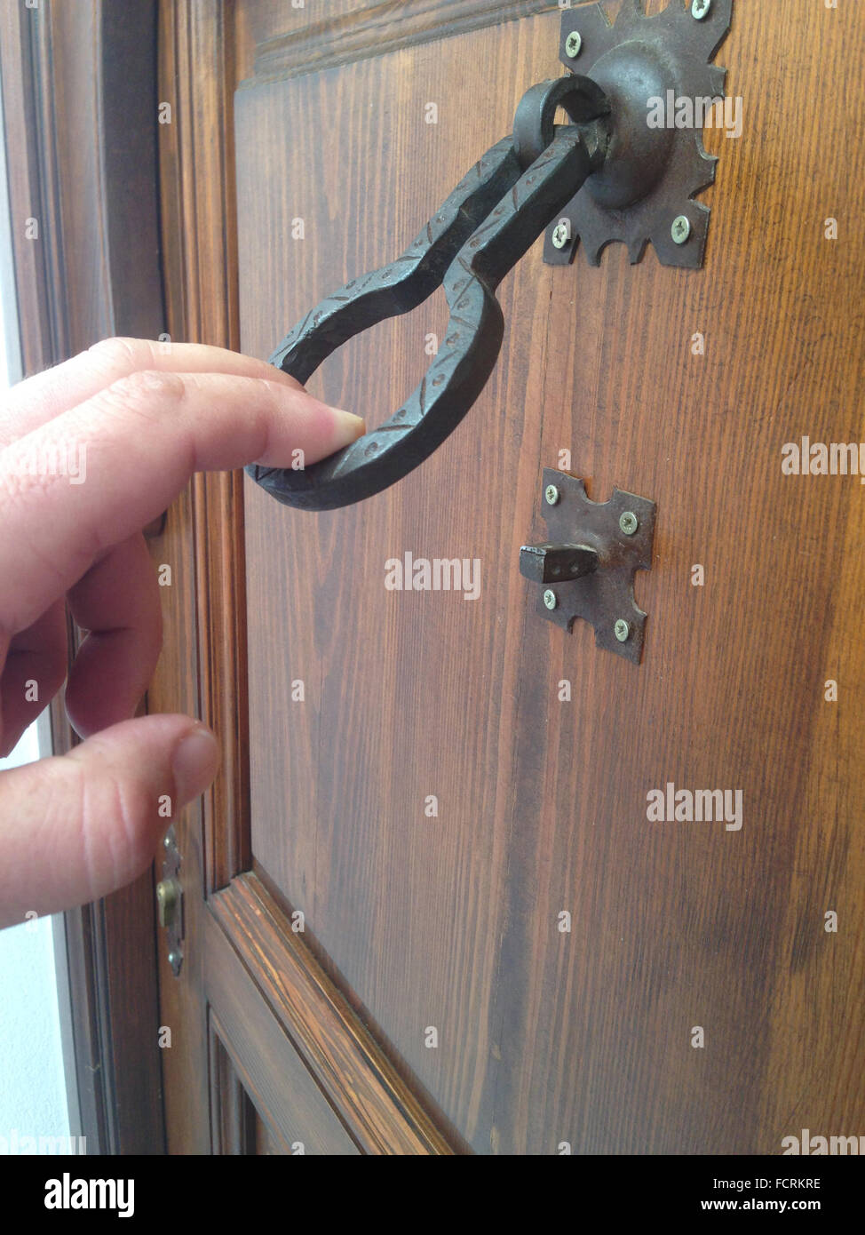 Man hand knocking with an old iron doorknocker. Selective focus Stock Photo
