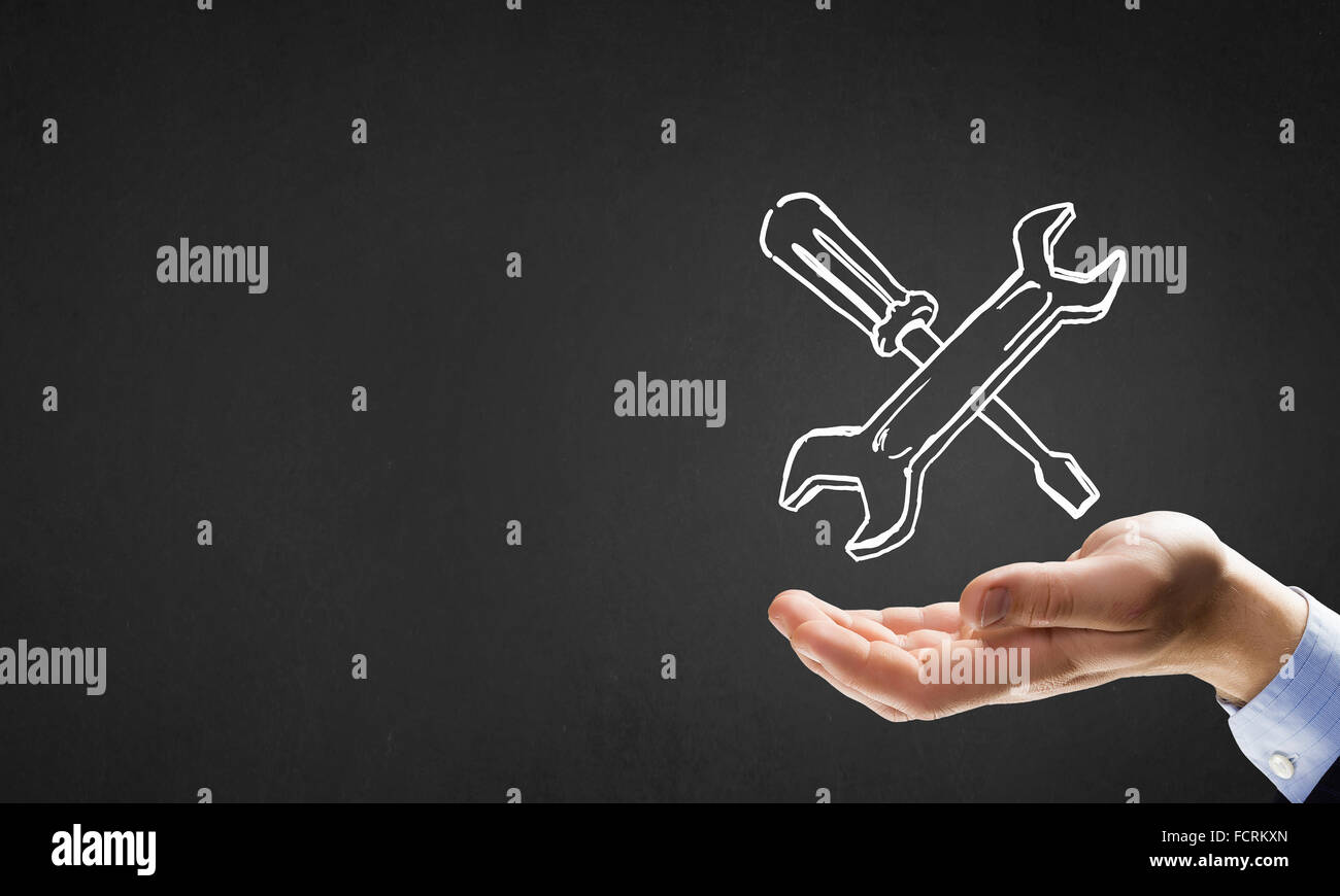 Businessman&rsquo;s hand holding tools over gray background Stock Photo - Alamy