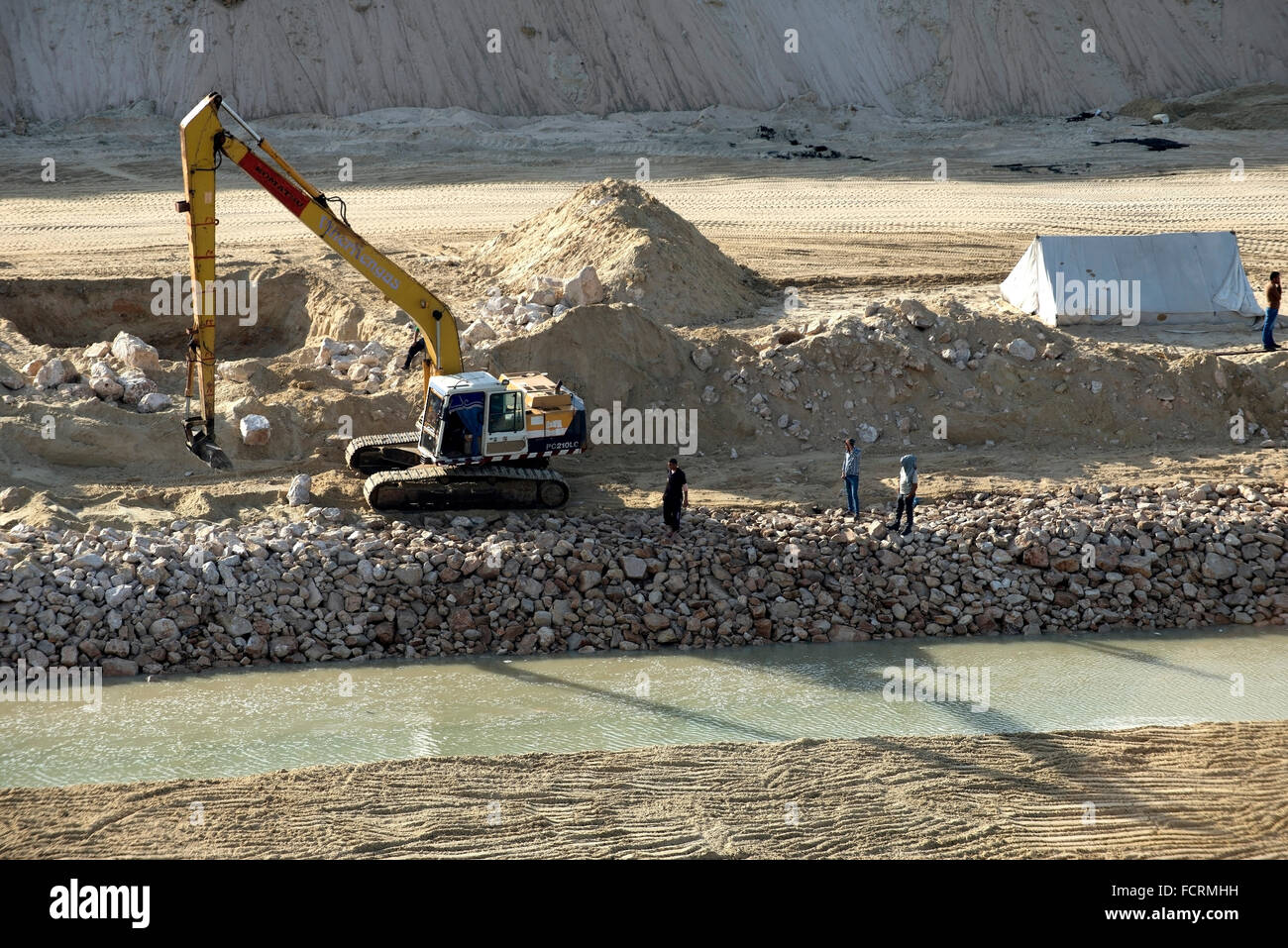 Egyptians watch on the shore at the start of a construction on the banks of the new Suez Canal. Stock Photo