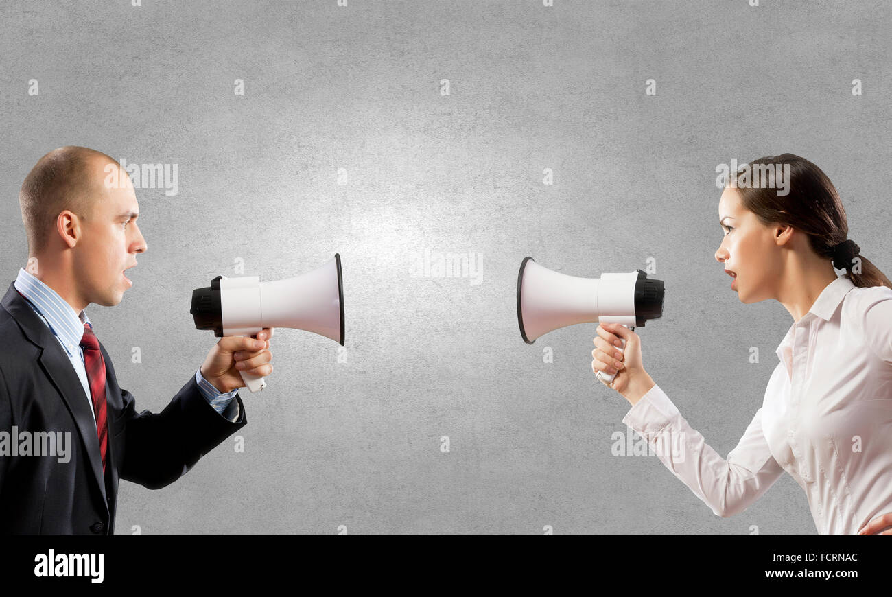 Young furious people screaming agressively in megaphone Stock Photo
