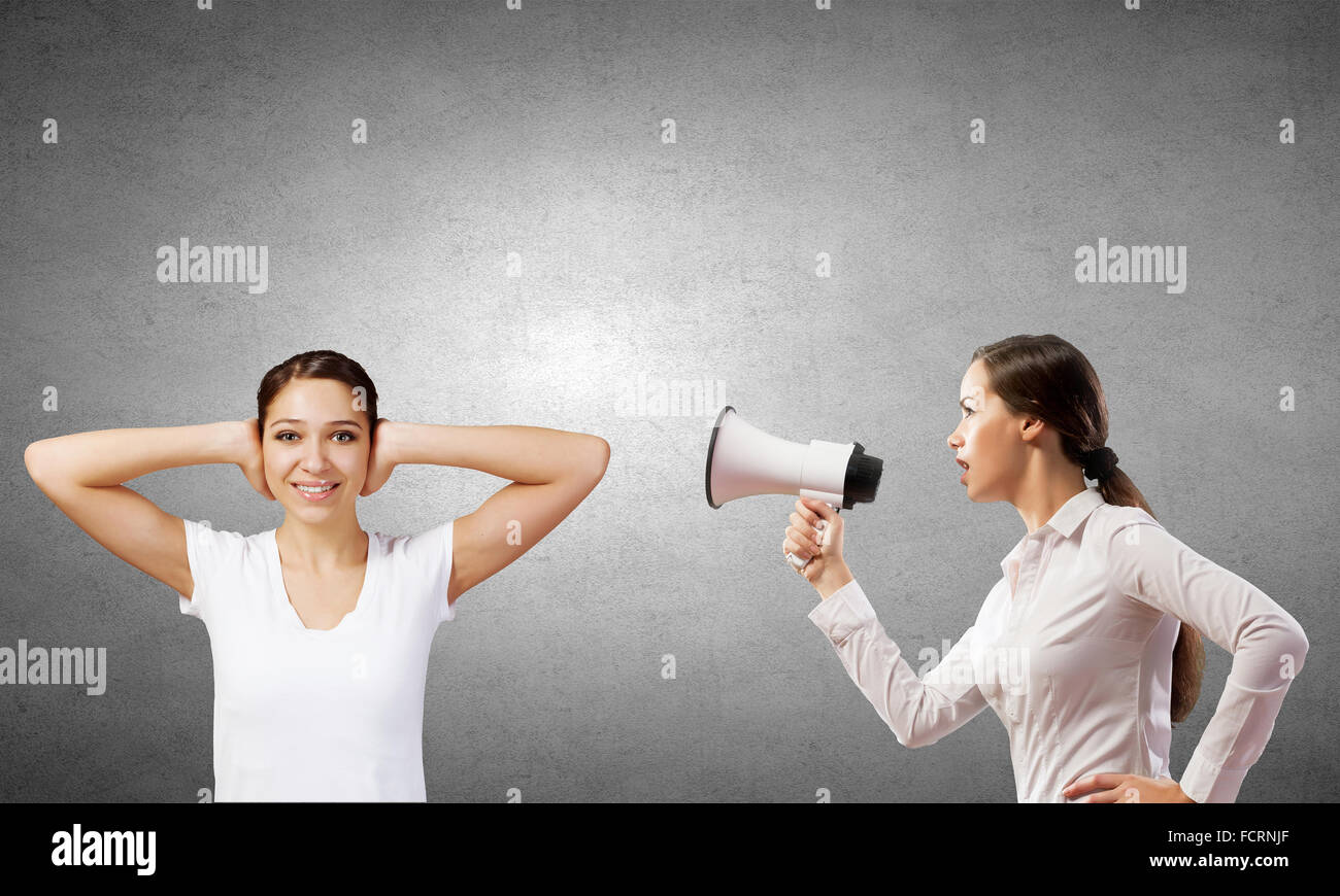 Young furious woman screaming agressively in megaphone Stock Photo