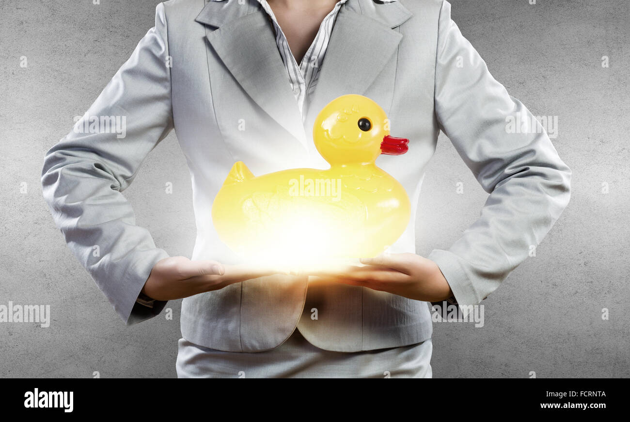 Businesswoman holding in hands yellow toy rubber or plastic duck Stock Photo