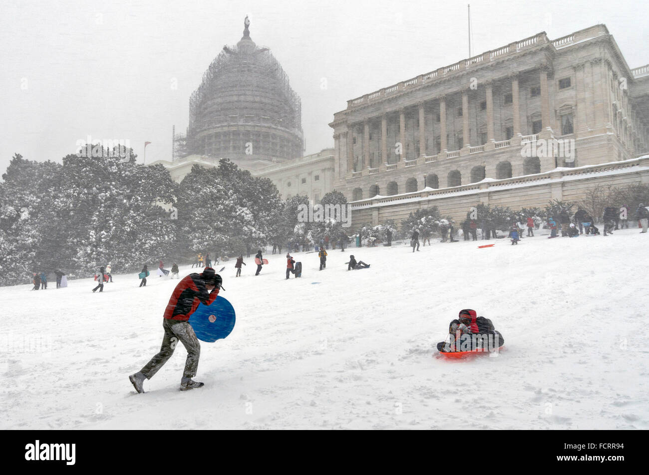 Washington DC, USA. 23rd January, 2016. Residents take advantage Winter Storm Jonas to ride snow sleds down the slope on Capitol Hill January 23, 2016 in Washington, DC. This was the first time it was legal to use the hill for sledding after Congress passed a bill allowing resident access to the grounds in snow. Stock Photo