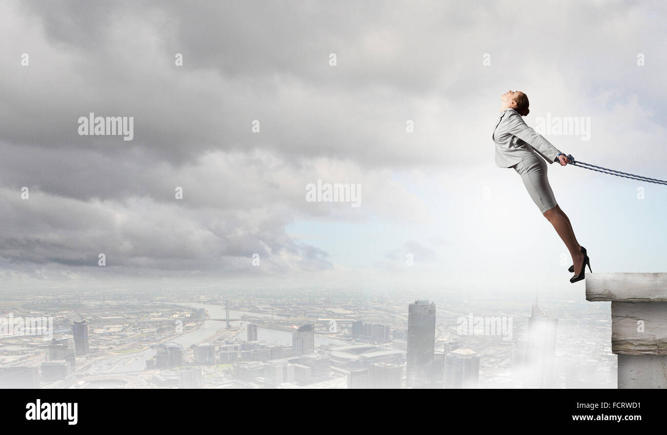 Young businesswoman with ropes on hands trying to fly Stock Photo - Alamy