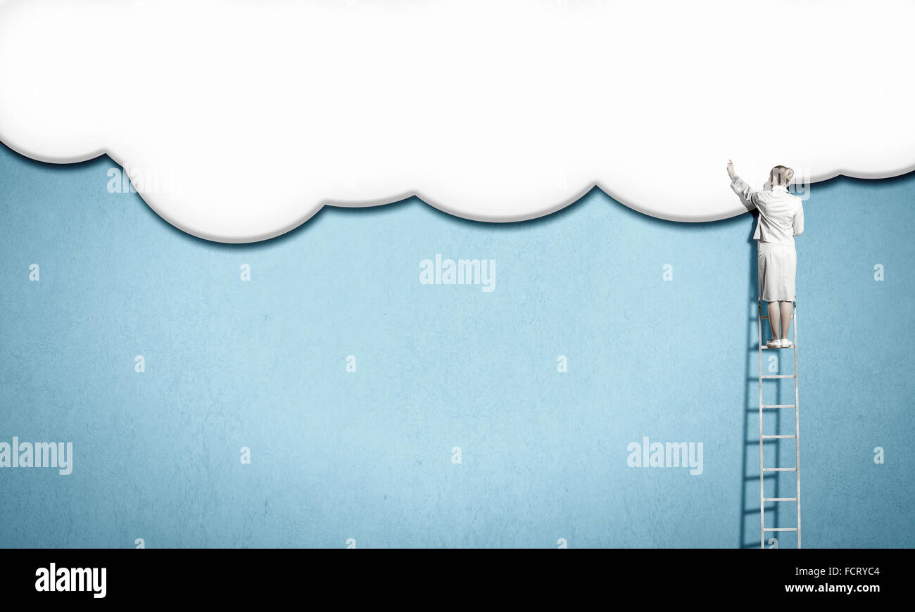Back view of businesswoman standing on ladder and reaching to cloud ...