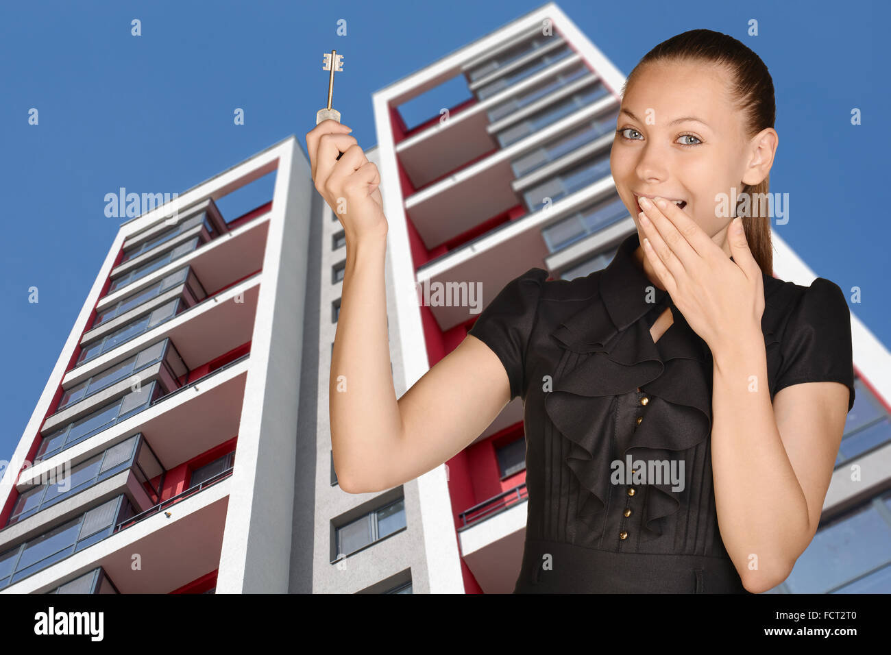 Joyful girl standing on background of building and is holding keys Stock Photo