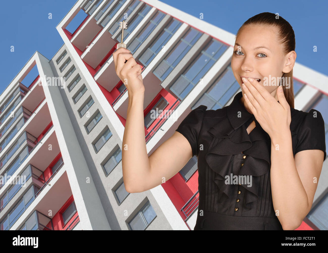 Successful girl standing on background of building and is holding keys Stock Photo