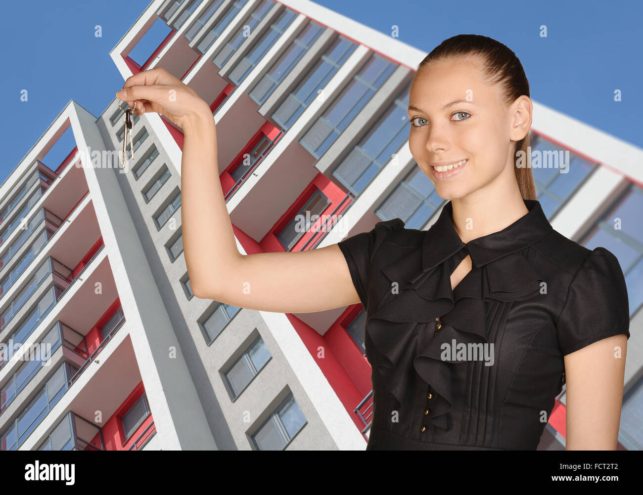 Young girl standing on background of building and is holding keys Stock Photo