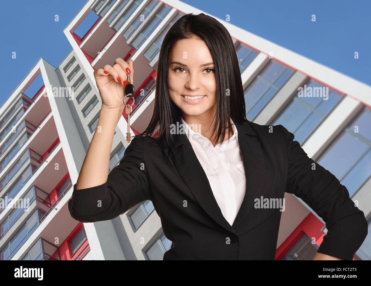 Beautiful girl standing on background of building and is holding keys Stock Photo