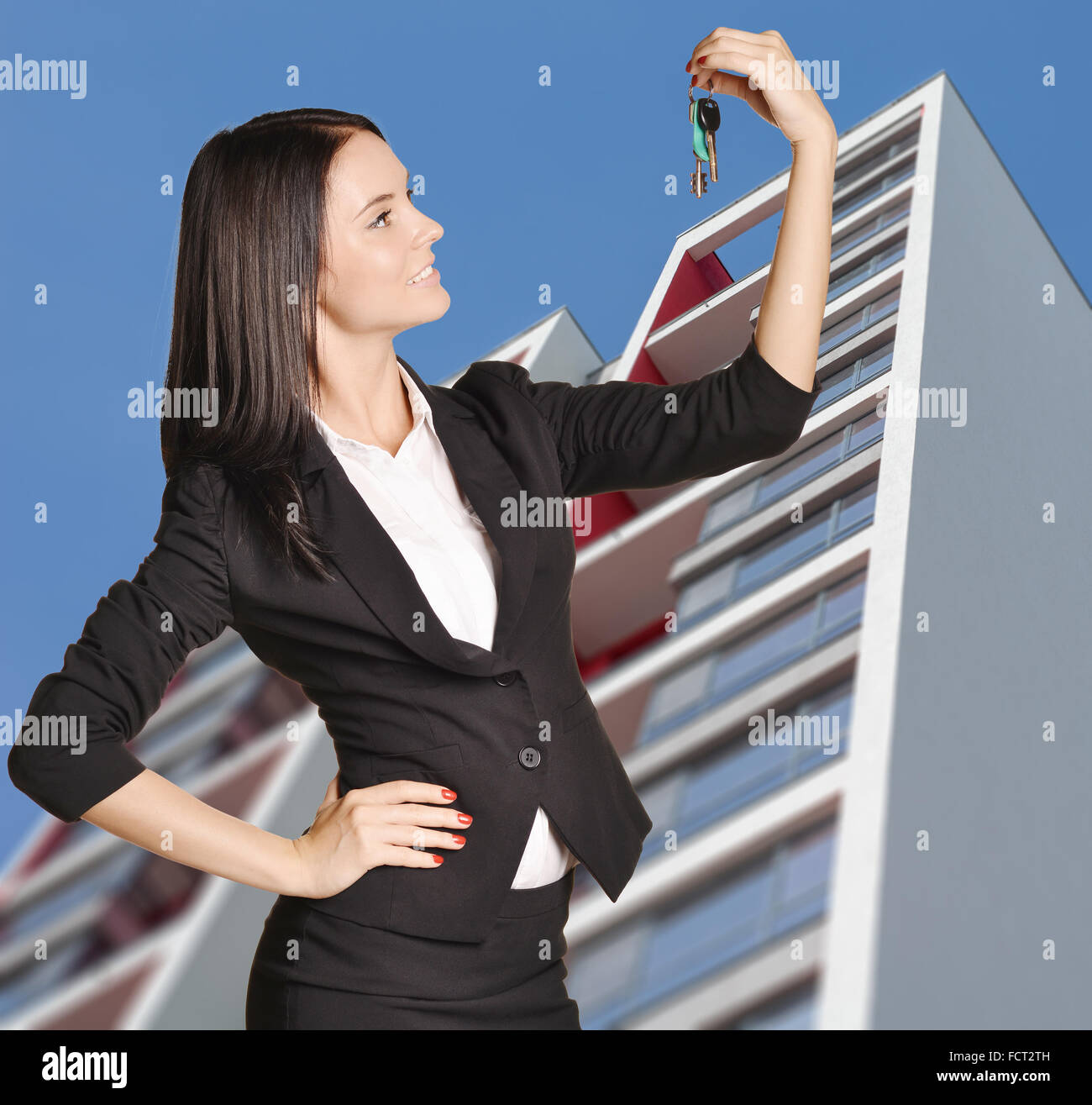 Woman standing on background of building and is holding keys from apartment Stock Photo