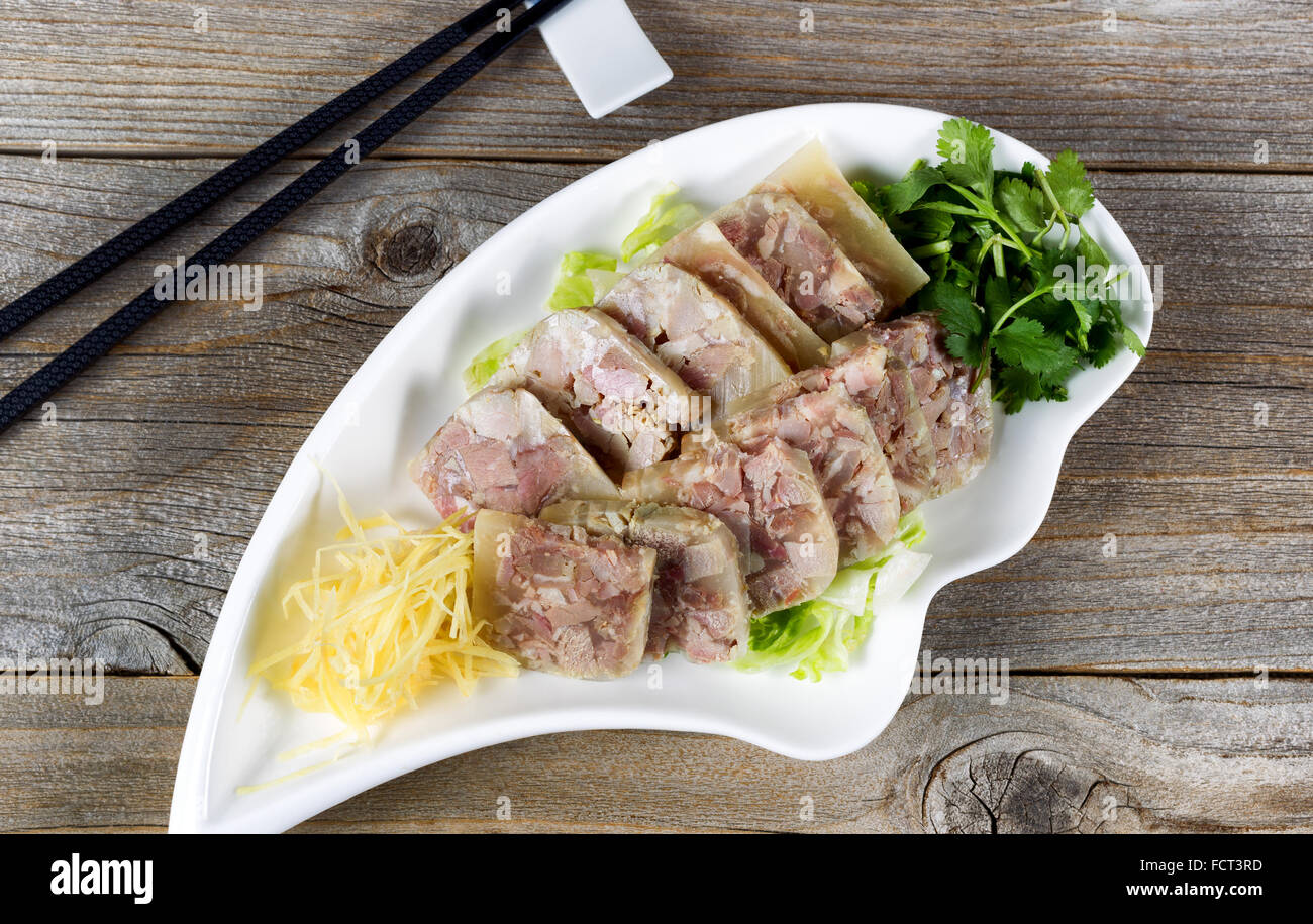 High angled view of glazed pork slices and herbs with chopsticks on rustic wood. Stock Photo