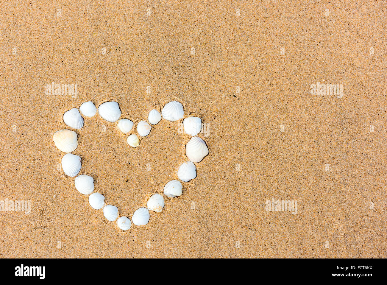 Heart Behind Shell sea shell heart on the beach. sand background Stock Photo - Alamy