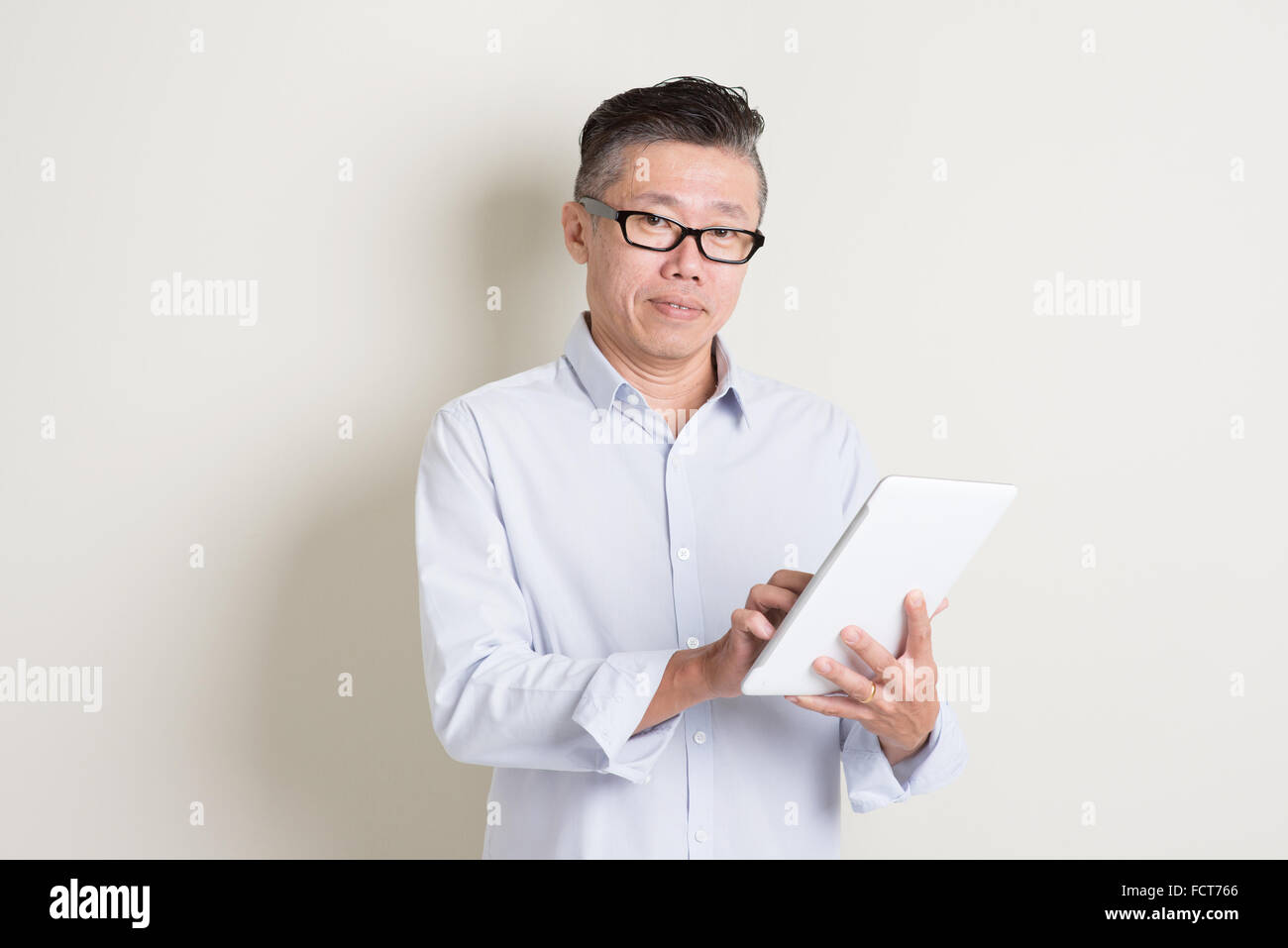 Portrait of single mature 50s Asian man in casual business using ...