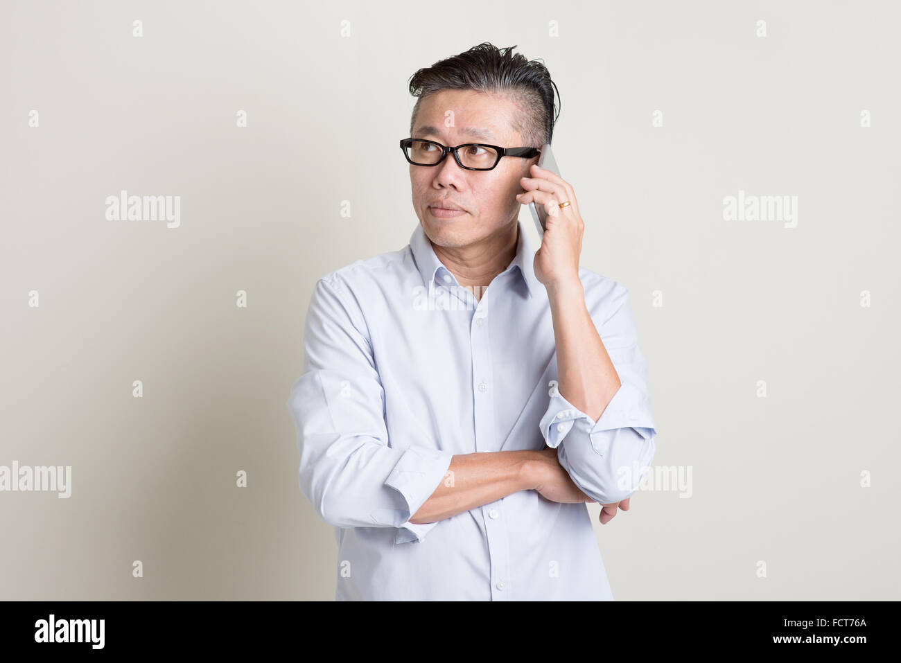 Portrait of single mature 50s Asian man in casual business calling on ...