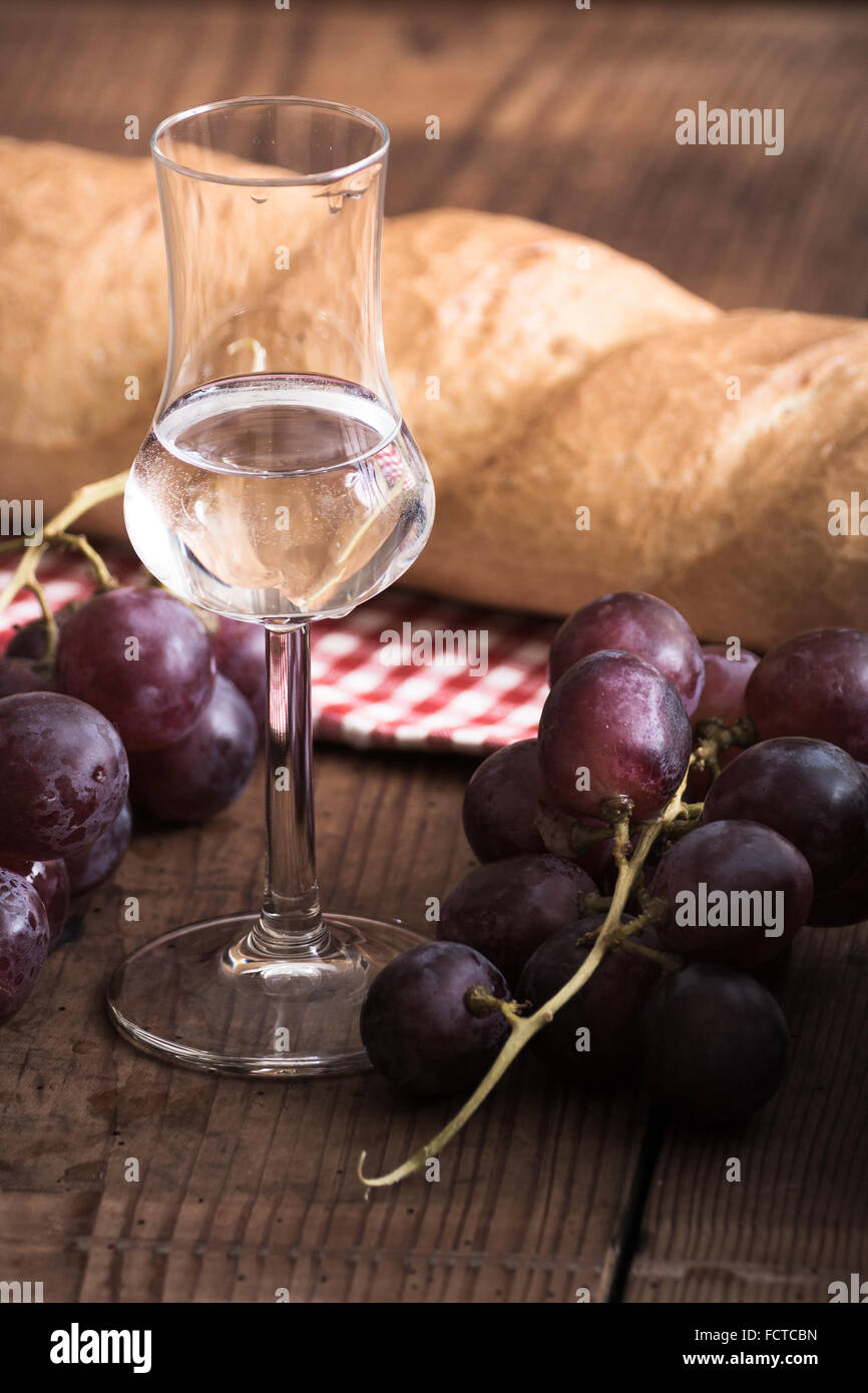 italien Grappa with Grape and Bread on wooden Table Stock Photo