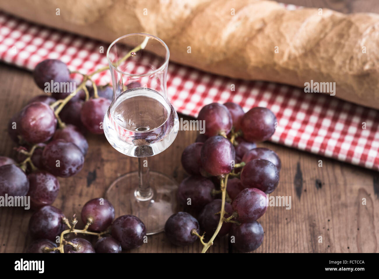 italien Grappa with Grape and Bread on wooden Table Stock Photo