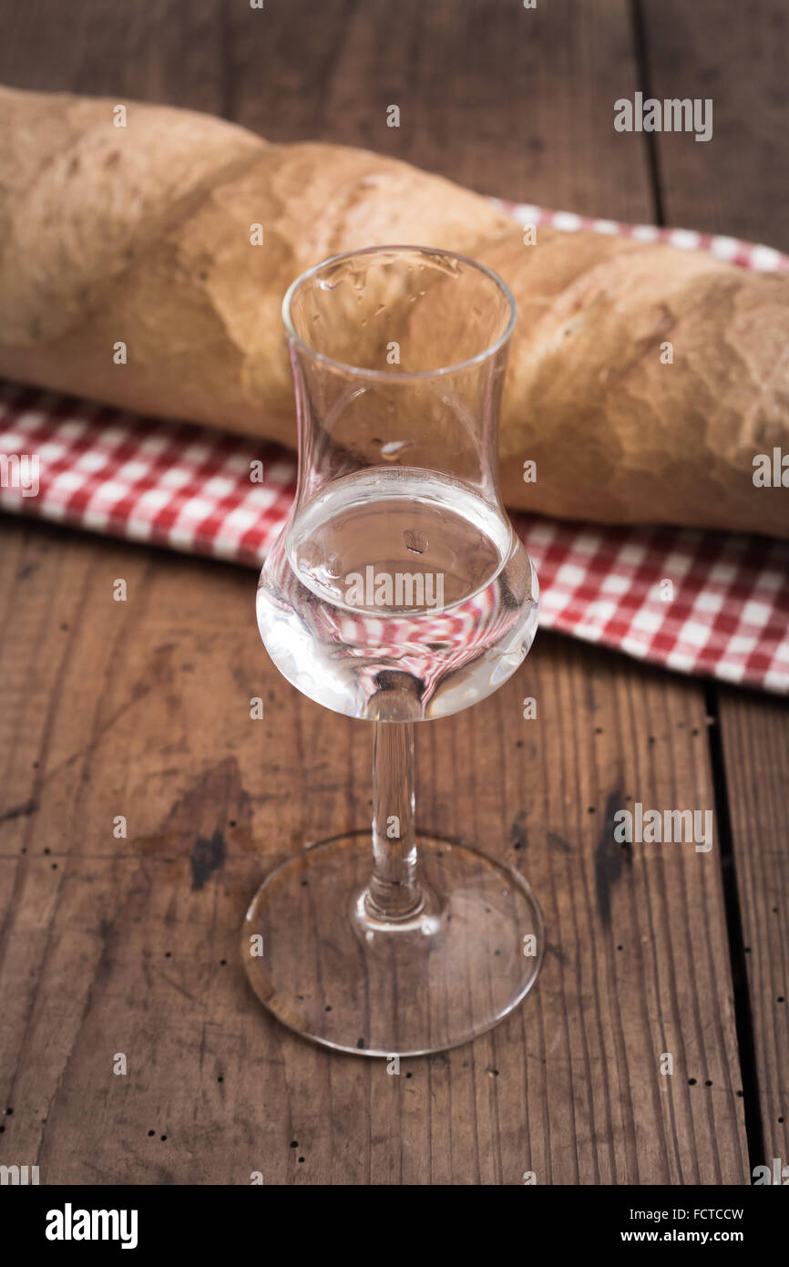 Glass of italien Grappa with Bread on wodden Table Stock Photo