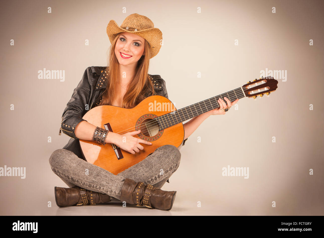 The beautiful girl in a cowboy's hat and acoustic guitar Stock Photo