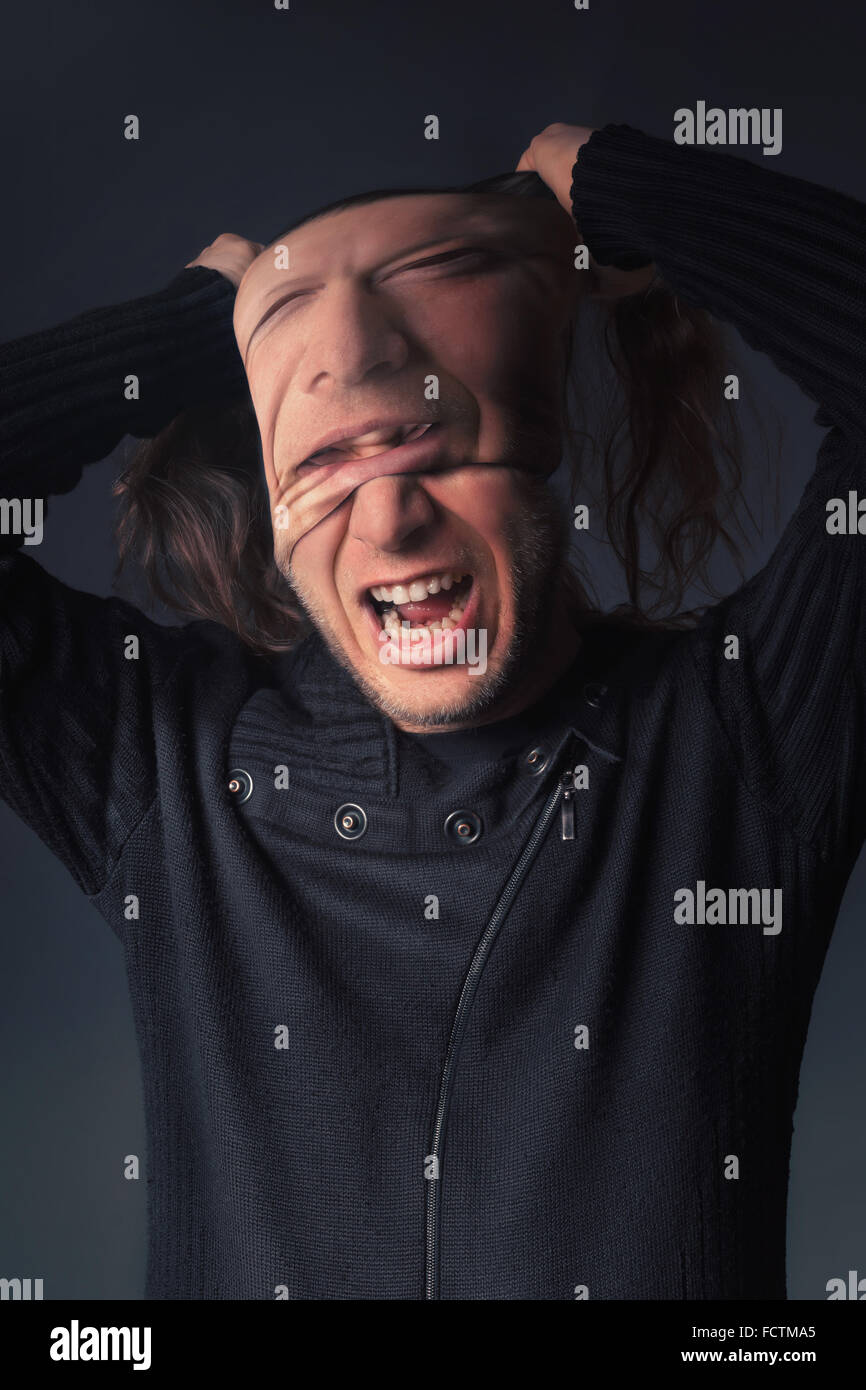 A man tears off the mask from his face Stock Photo