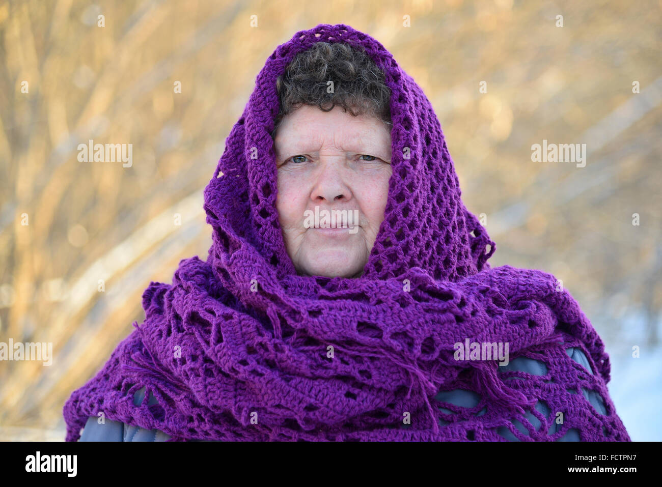 elderly woman in  purple  knitted shawl on her head Stock Photo