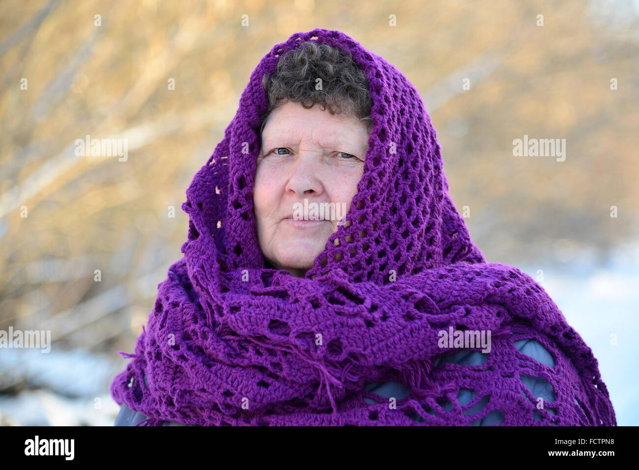 elderly woman in  purple  knitted shawl on her head Stock Photo