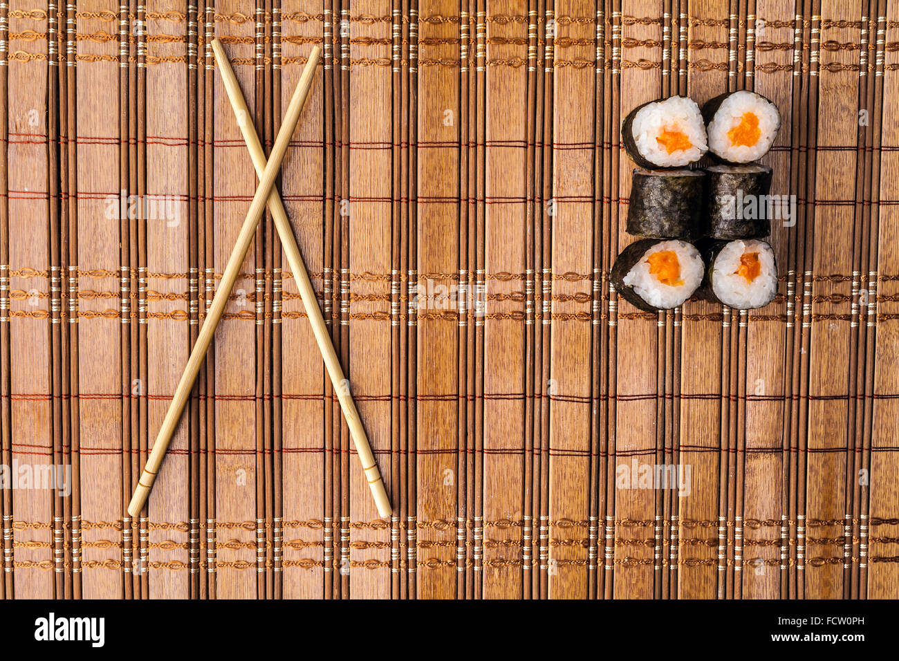 https://c8.alamy.com/comp/FCW0PH/chopsticks-and-sushi-roll-on-bamboo-mat-background-menu-FCW0PH.jpg