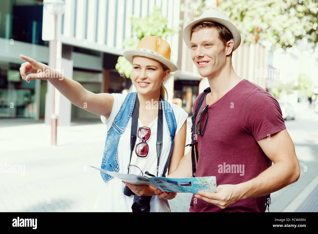 Happy young couple as tourists with a map Stock Photo - Alamy